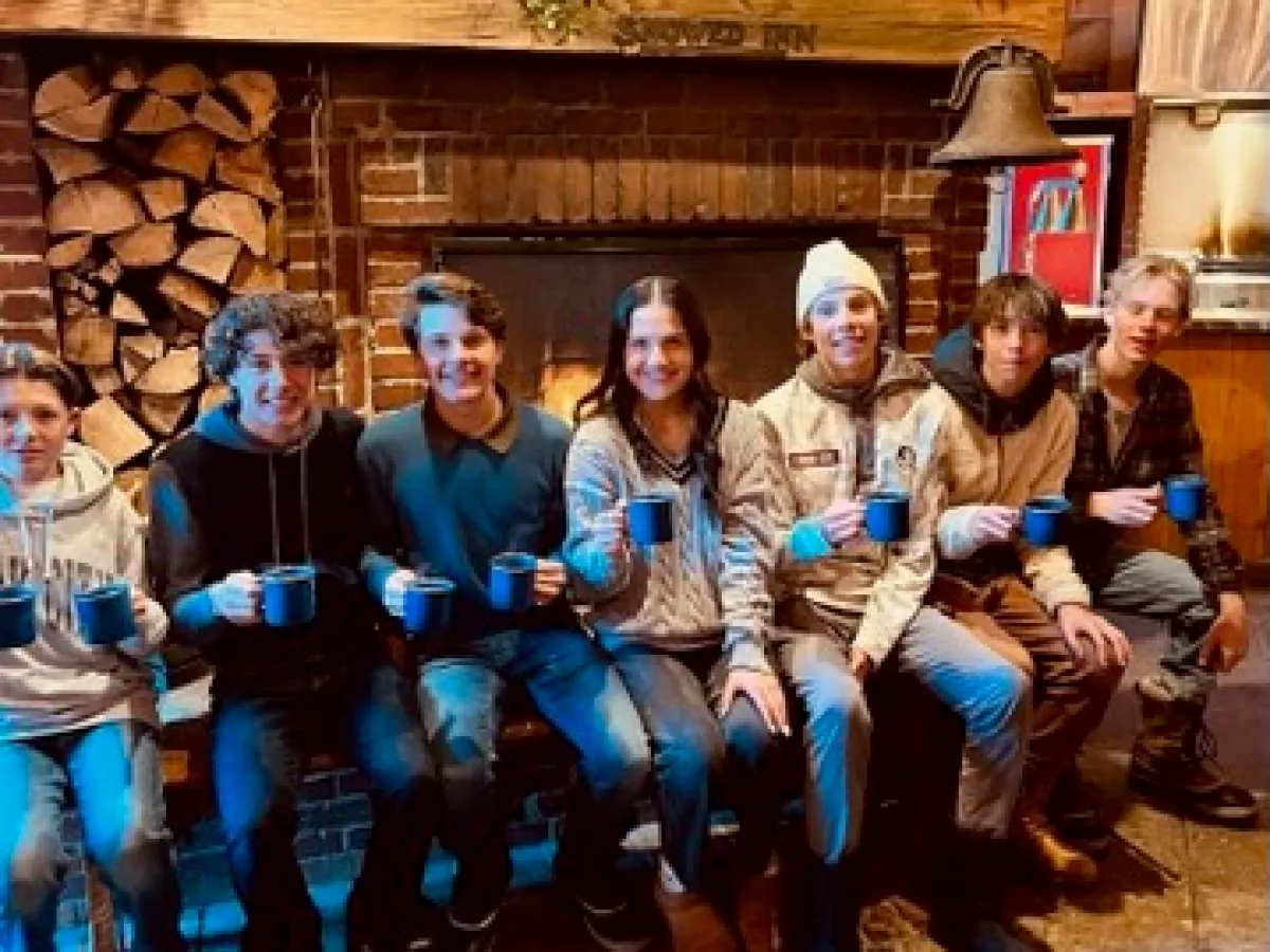 a group of kids sitting on a bench in front of a fireplace