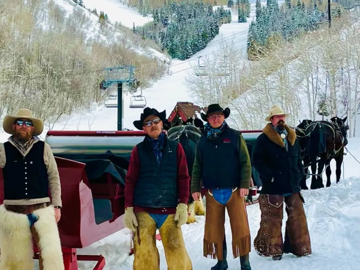 a group of cowboys that are standing next to a sleigh
